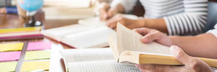 Young students classmates help friend catching up workbook and learning tutoring in a library, education and school concept