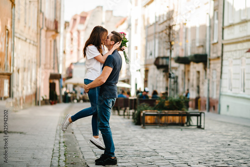 Photographie Smiling Young couple with a bouquet of flowers in love hug each other in love outdoors