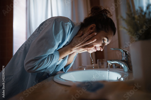 Fotografía Smiling woman washing her face in the evening.