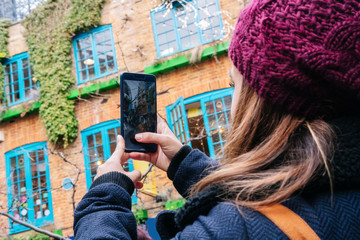 Wall Mural - Girl takes a picture with the mobile phone in the street of a picturesque town