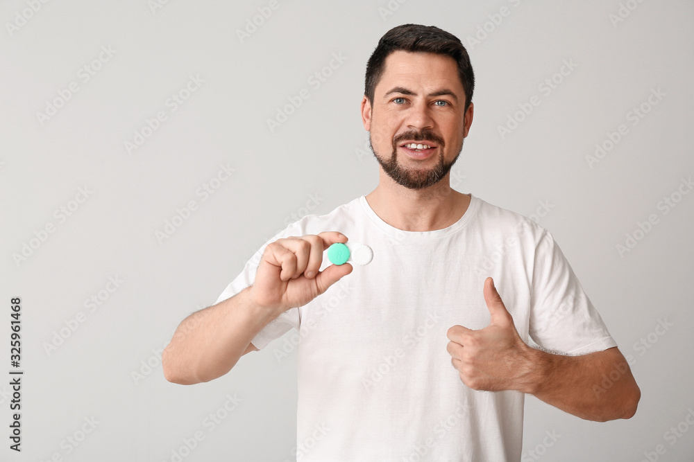 Man with contact lenses showing thumb-up on light background