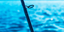 Fishing Rod Spinning Rod With The Line Close-up. Fishing Rod. Fishing Tackle. Fishing Spinning Reel Over Blue Ocean Water