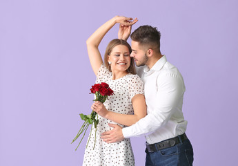 Canvas Print - Happy young couple with bouquet of flowers on color background