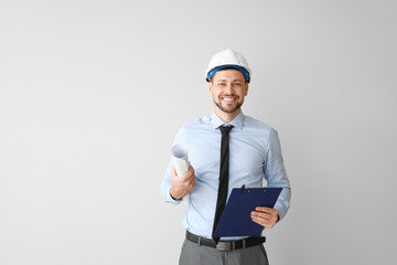 Male engineer with drawing on light background