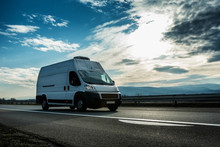 White van transporting through highway on bright sunny sunset.