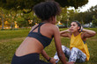 © StratfordProductions - Fit young woman doing crunches with her exercise female partner on green grass during a workout session - young determined and motivated woman doing exercise