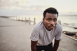 © StratfordProductions - Young athletic man in sportswear looking exhausted taking rest from jogging at the seaside in morning