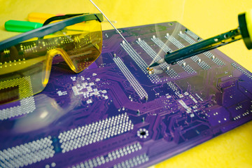 Soldering iron repairs the motherboard,blurred background