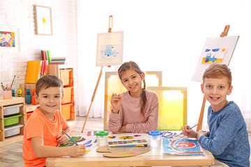 Wall Mural - Cute little children painting at table in room