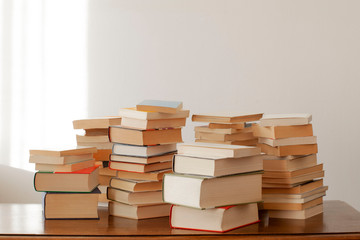 stack of piled books rest on a wooden table with copy space for your text