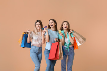 Sticker - Young women with credit cards and shopping bags on color background