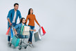 © My Ocean studio - Lovely day. Young father and mother are excited while being on their shopping spree together with their beautiful little daughter, who is sitting in a shopping cart with lots of paper bags.