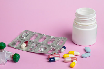 Wall Mural - pills blister, pill bottle and different colored medicine capsules on a pink background