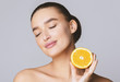 Delighted young pretty woman with closed eyes holding orange half