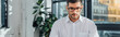 © LIGHTFIELD STUDIOS - panoramic shot of professional male translator in eyeglasses working in modern office
