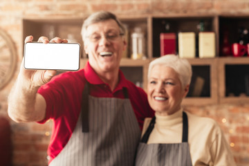 Wall Mural - Happy senior couple taking selfie on modern smartphone with white screen