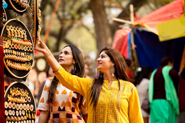 Two women shopping for earrings at street market