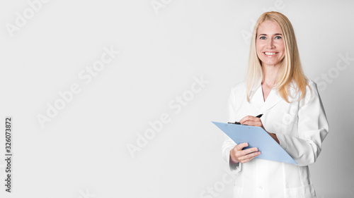 Photographie Middle aged woman holding clipboard writing diagnosis