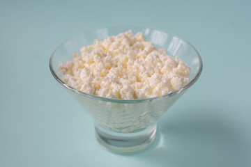 Homemade rustic crumbly cottage cheese on a blue background.