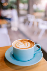 Wall Mural - One cappuccino on a wooden table at a coffee shop