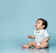 © FAB.1 - Little toddler in white bodysuit as a vest with bow-tie, barefoot. He is sitting on the floor against blue background. Close up