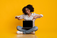 Afro Woman Pointing At Laptop With Blank Screen On Her Laps