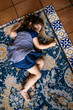 © Maskot - High angle view of girl lying on carpet