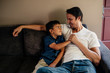© Maskot - Happy father with son sitting on sofa at home
