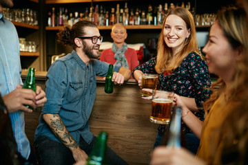 Canvas Print - Group of friends drinking beer, chatting and having good time at pub. Night out.