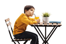 Pensive Boy Drinking Juice At A Table And Looking Away