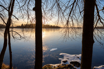 Wall Mural - Wintry landscape from Finland during February. Cold afternoon sunset scenery. Frozen lake shore.