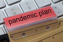 The Words  Pandemic Plan Can Be Seen On The Label Of A Brown Hanging Folder. The Hanging Folder Is On A Computer Keyboard.