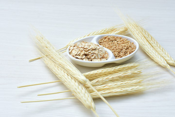 Oat grains and flakes accompanied by wheat ears in containers for display