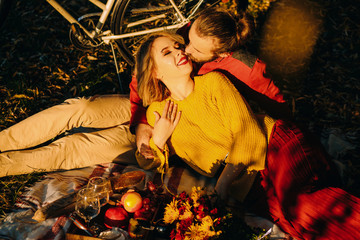 Amazing family couple have picnic in autumnal park. Man and woman sitting on picnic blanket. Bicycle ride and active lifestyle. Romantic picnic concept