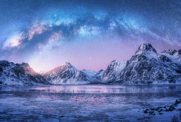milky way above frozen sea coast and snow covered mountains in winter at night in lofoten islands, n