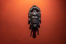 Wooden African Mask On A Stone Wall Background, Tanzania, Africa. Close Up