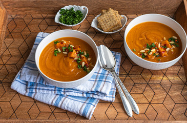 Wall Mural - Sweet potato soup in a white bowl with crackers on wooden tray 