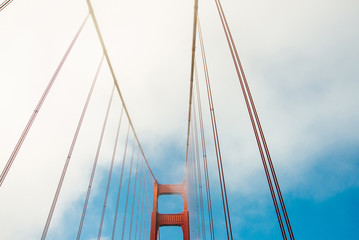 Poster - Close up of single tower of Golden Gate Bridge in white clouds San Francisco, USA, bottom view