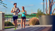 © astrosystem - Modern woman and man jogging / exercising in urban surroundings near the river.