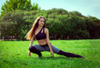 © Elena - white young woman in sportswear doing a stretch on the grass