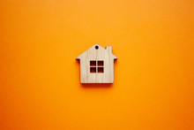 House, Insurance And Mortgage, Buing And Rent Concept. Small Wooden House Toy On Orange Background Top View