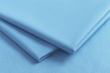Closeup Of A Stack Of Folded Blue Fabric With Shallow Depth Of Field On A Blue Woven Background
