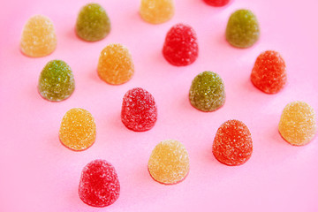 round sweet multi-colored candy marmalade in sugar sprinkles on pink background