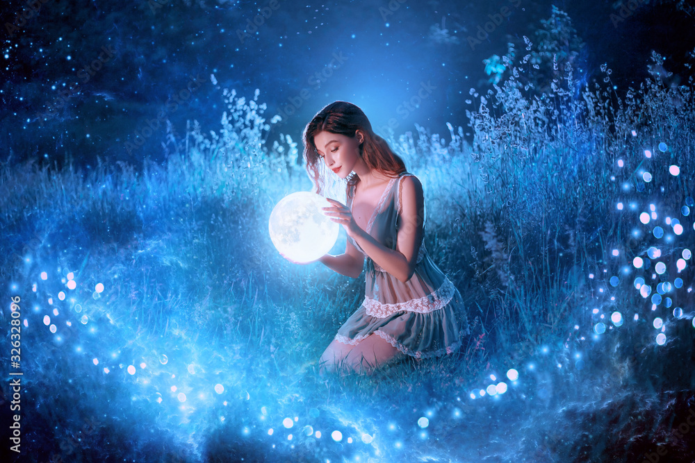 Fairytale sorceress holds in hands magical ball planet universe space sitting in night forest. Goddess with long red hair in short sexy blue dress. Backdrop flying bright sparkle stars white grass fog - obrazy, fototapety, plakaty 