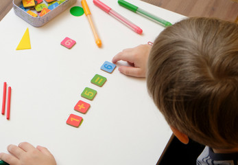 Little boy child preparing for elementary school doing simple math exercises.