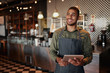 © StratfordProductions - Cheerful young male owner holding digital tablet while standing in cafe