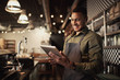 Portrait of successful young afro-american cafe owner standing behind counter using digital tablet