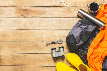 Wall Mural - Boots for trail, binoculars, trekking accessories on a wooden background. The concept of hiking, tourism, camp, mountains, forest. Banner. Flat lay, top view