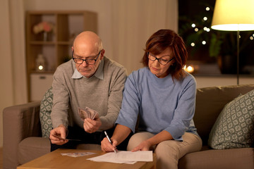 Sticker - family, savings and people concept - smiling senior couple with bills counting money at home