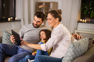 Poster - family, people and technology concept - happy smiling father, mother and little daughter with tablet pc computer at home at night